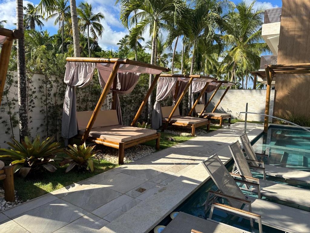 eine Reihe von Liegestühlen neben einem Swimmingpool in der Unterkunft Amura Carneiros apartamento 3 quartos com piscina privativa in Praia dos Carneiros