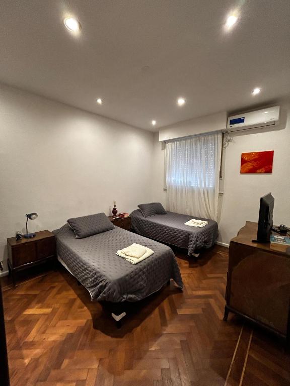 twee bedden in een kamer met houten vloeren bij Casa Barracas, habitación privada in Buenos Aires