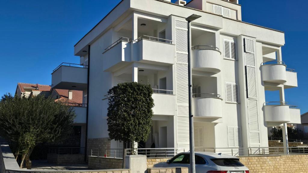 een wit gebouw met een auto ervoor geparkeerd bij CRYSTAL WAVE Apartments in Novalja