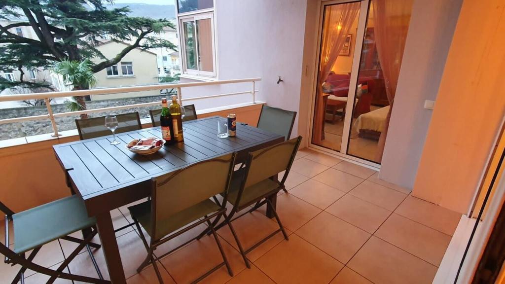a table with chairs and bottles of wine on a balcony at La terrasse de Jeanne in Millau