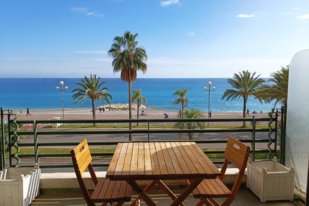 - une table et des chaises en bois avec vue sur la plage dans l'établissement Charming T1 with terrace and sea view, à Nice
