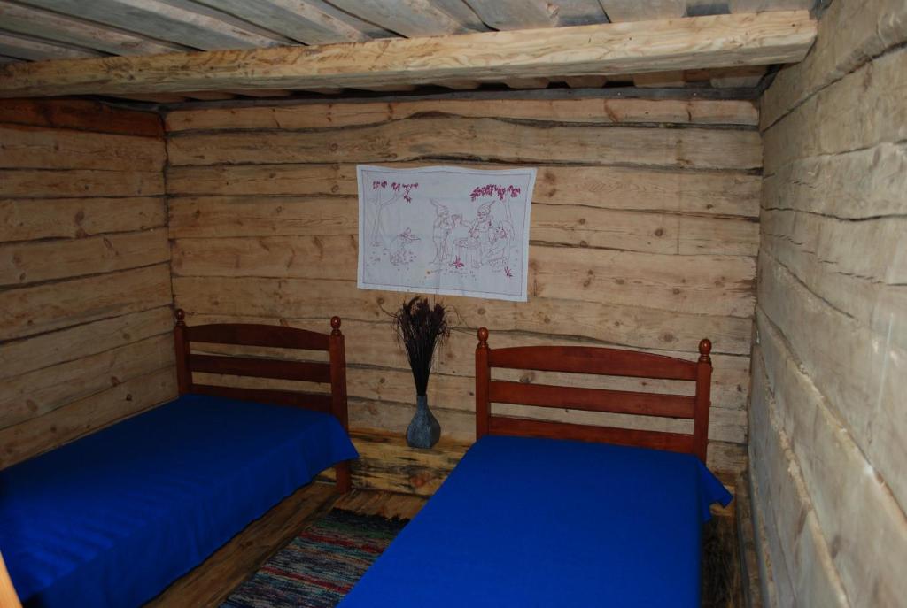 two beds in a room with wooden walls at Hallikivi Tourist Farm in Vennarti