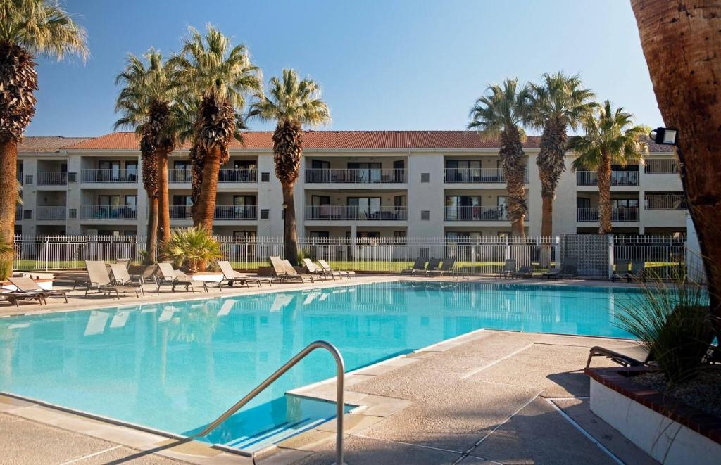 a swimming pool in front of a hotel with palm trees at Cozy 3 Br Las Palmas Resort Hot Tub Pool & Parking in St. George