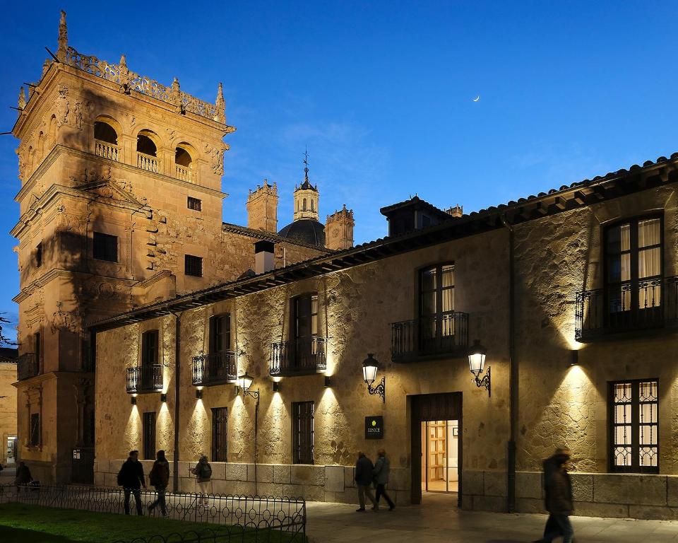 a building with a tower and people walking in front of it at Eunice Hotel Gastronómico in Salamanca