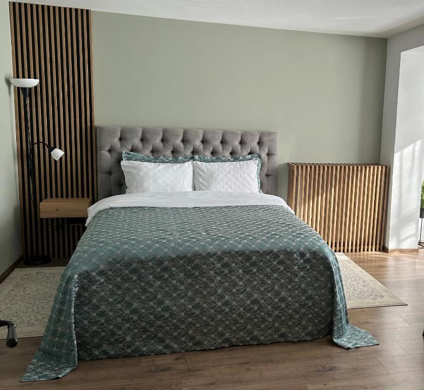 a bedroom with a large bed with a green comforter at VYO Studio in Braşov