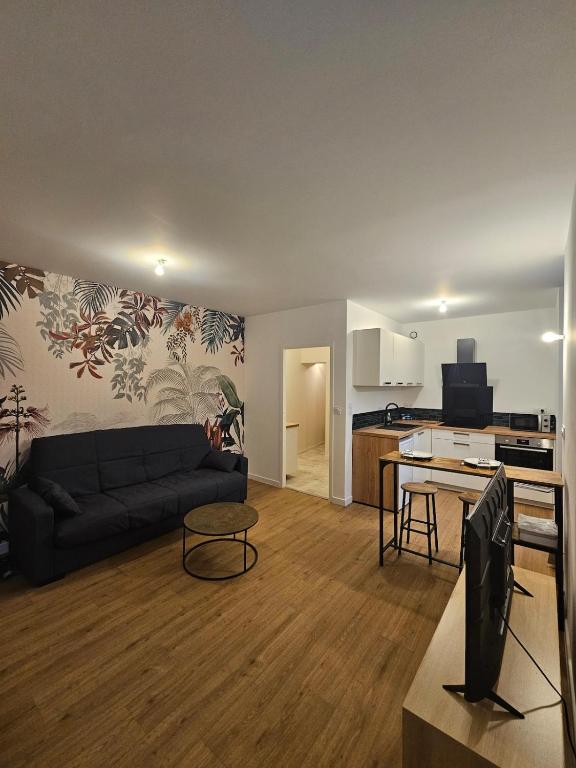 un salon avec un canapé noir et une cuisine dans l'établissement L'Authentique - Studio 3, à Loudéac