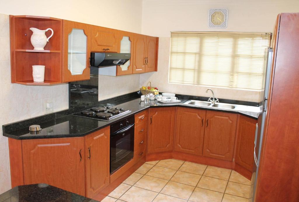 una cocina con armarios de madera y encimeras negras en Lincoln Cottages BnB & Self-Catering, en Pietermaritzburg