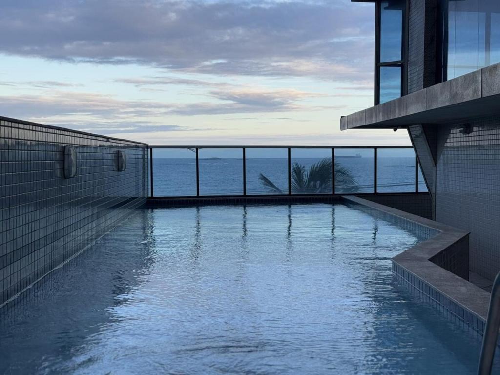 a swimming pool with a view of the ocean at Seu apartamento frente mar in Vila Velha
