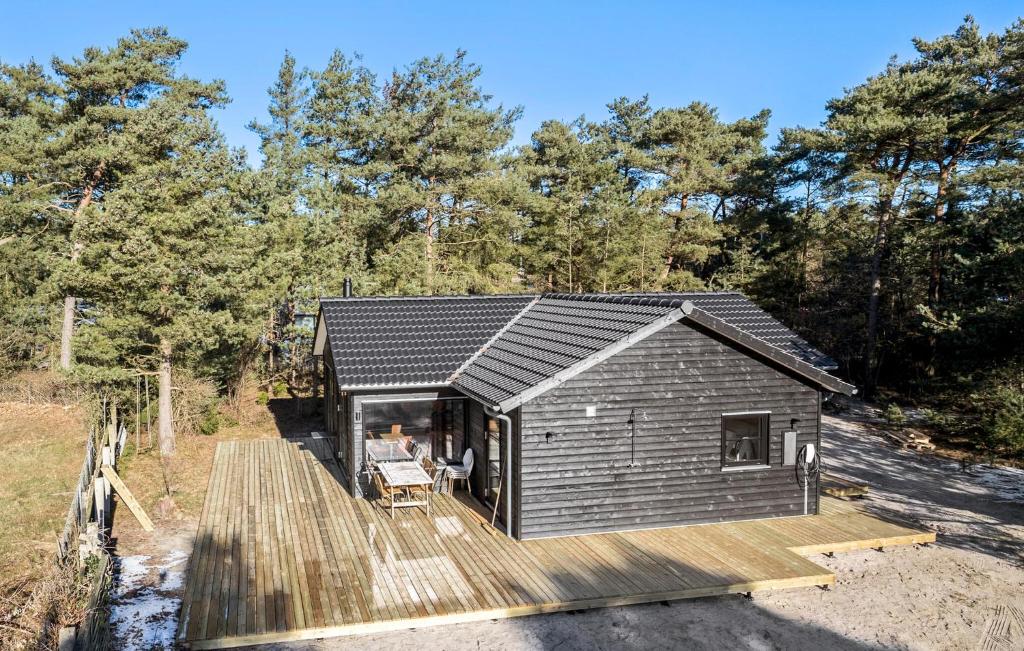 a small cabin with a wooden deck in the woods at 3 Bedroom Lovely Home In Nexø in Neksø