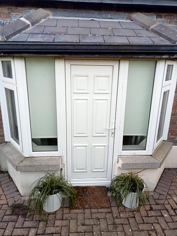 a white garage with two windows and two potted plants at The Studio in Dublin