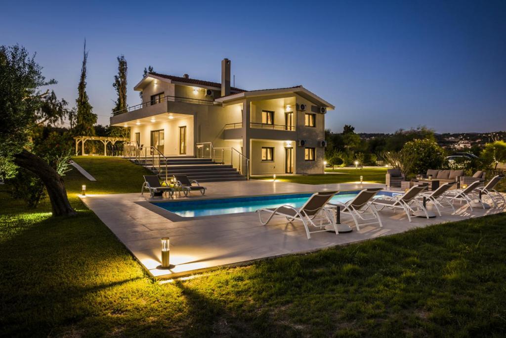 a house with a swimming pool and chairs in the yard at Villa Astoria Exclusive luxury villa in Svoronata with breathtaking views and private grounds in Kefallonia