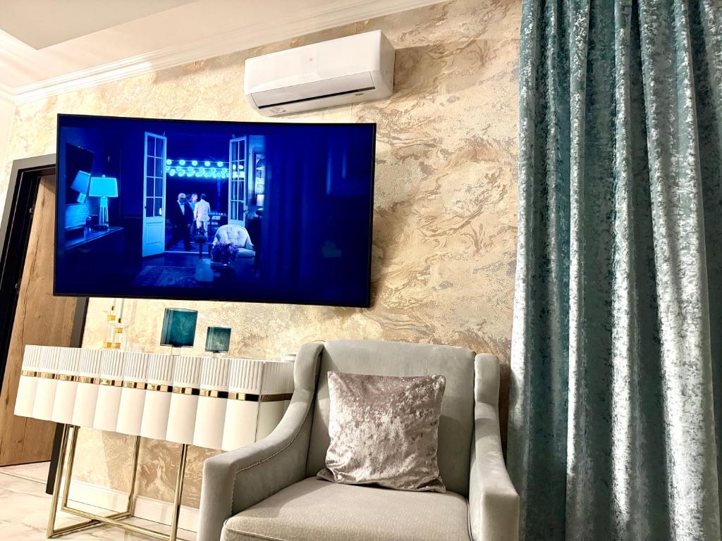 salon z krzesłem i telewizorem na ścianie w obiekcie White Lotus w Nyíregyházie