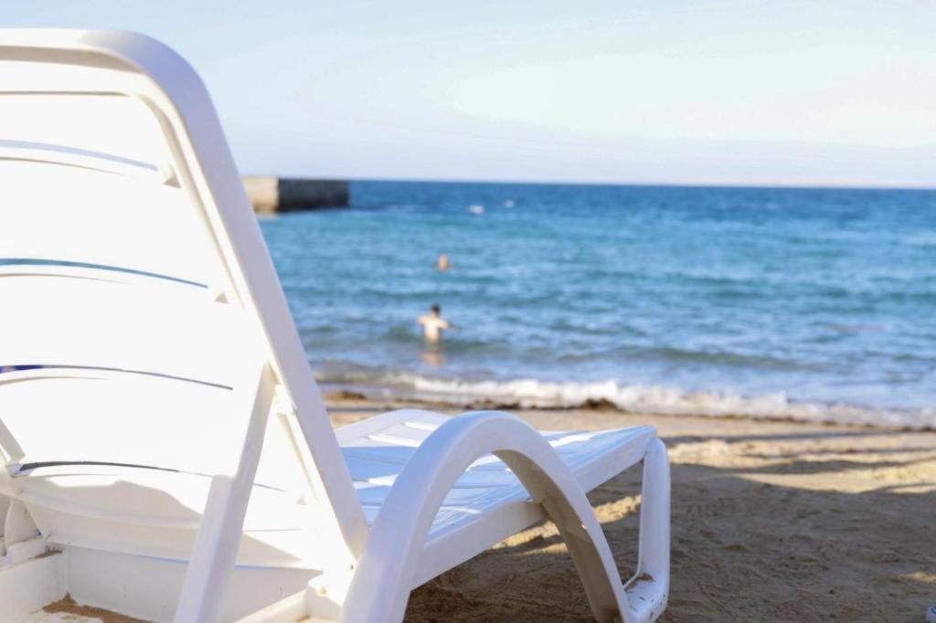 a white chair sitting on a beach with the ocean at Juliana Beach Aqua park in Hurghada