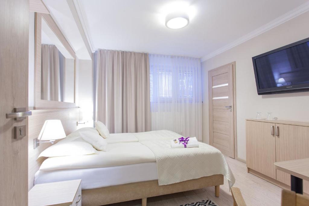 a white bedroom with a bed and a flat screen tv at Villa Anna in Gdańsk