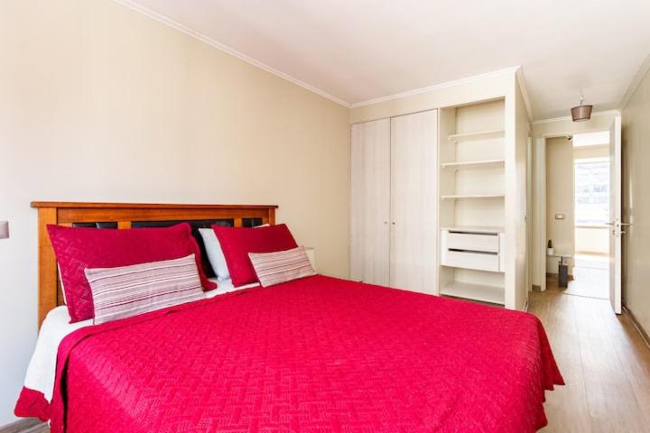 a bedroom with a large red bed with red pillows at Departamento centro hermoso 2 personas in Santiago