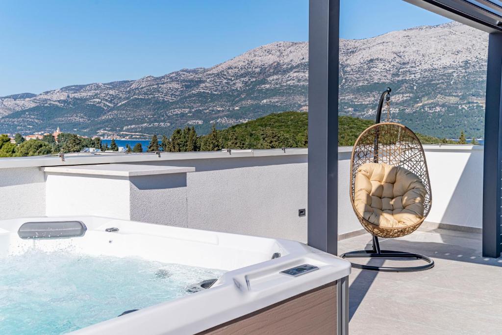 a bathroom with a tub and a rattan chair at Penthouse apartment Optimum in Korčula