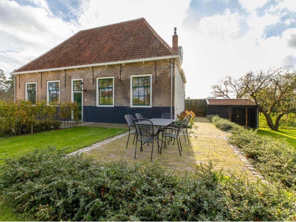 a table and chairs in front of a house at Farmhouse in Zeeland with Windmill Views in Heinkensand