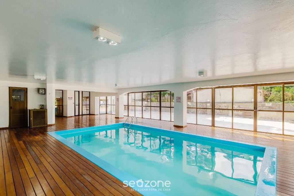 ein großer Pool in einem großen Zimmer mit Fenstern in der Unterkunft Unidades em Prédio com Piscina em Gramado - MDC in Gramado