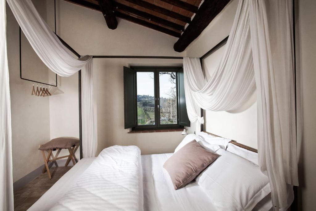Schlafzimmer mit einem Bett mit weißen Vorhängen und einem Fenster in der Unterkunft Salcheto WineHouse in Montepulciano