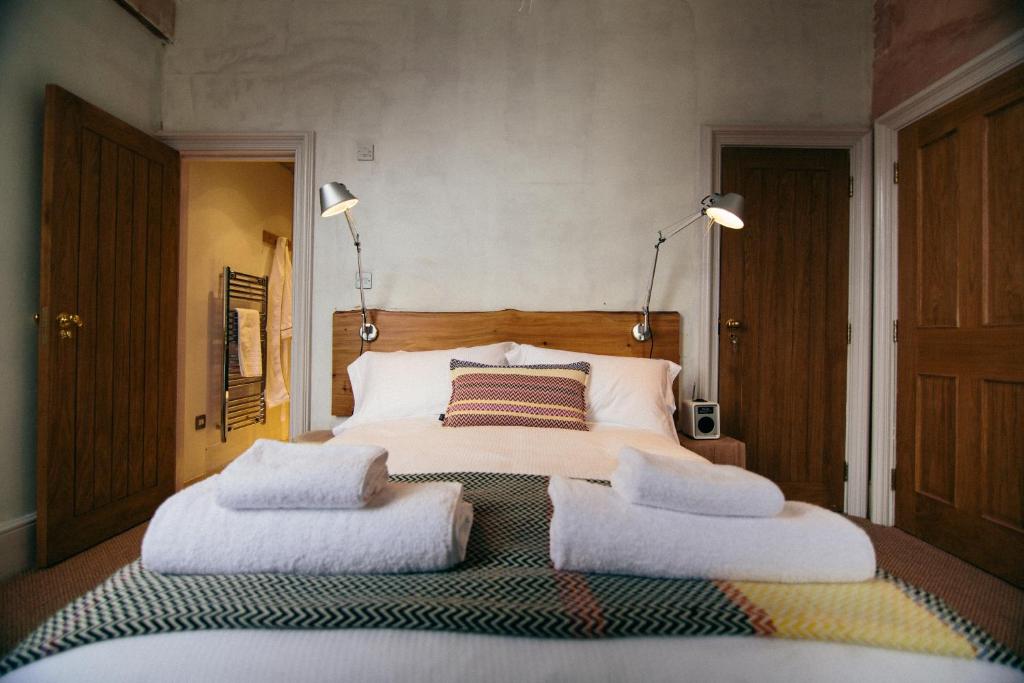 a bedroom with a large bed with three pillows on it at The Culpeper Bedrooms in London