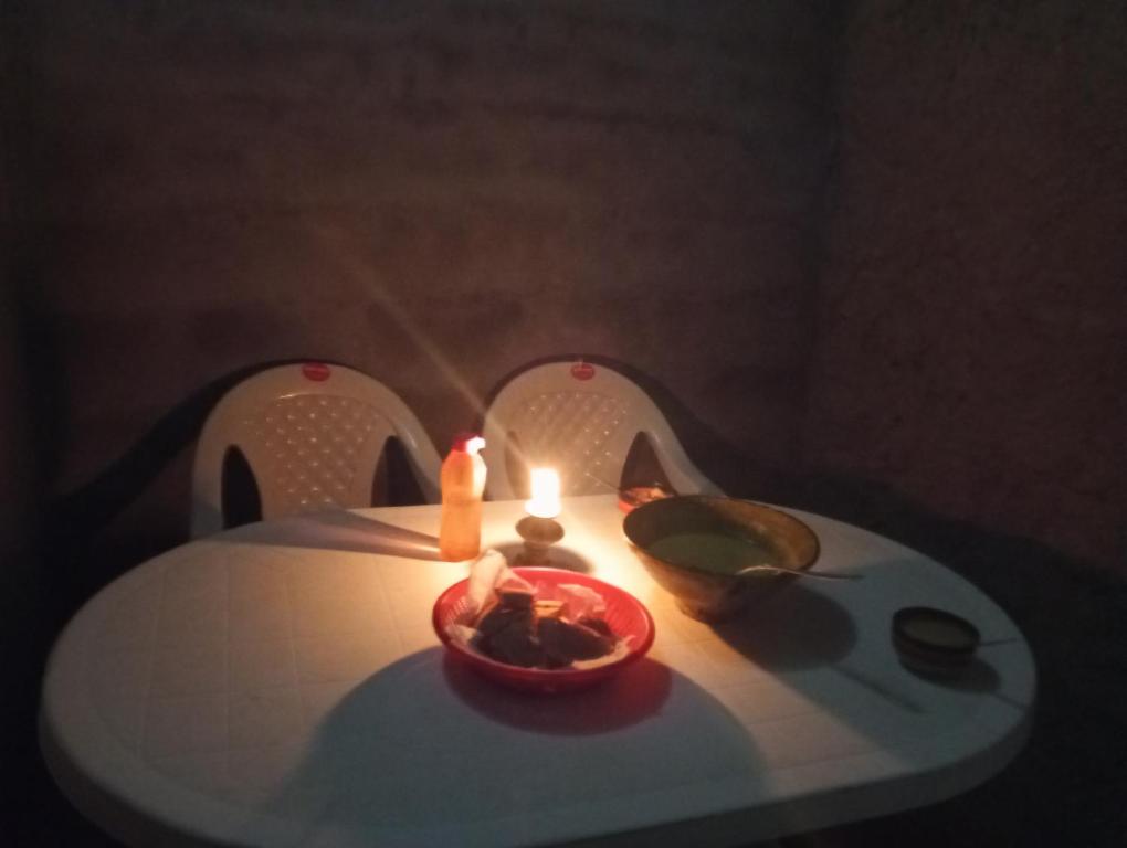 a table with two chairs with a candle on it at dar Brahim in Mhamid