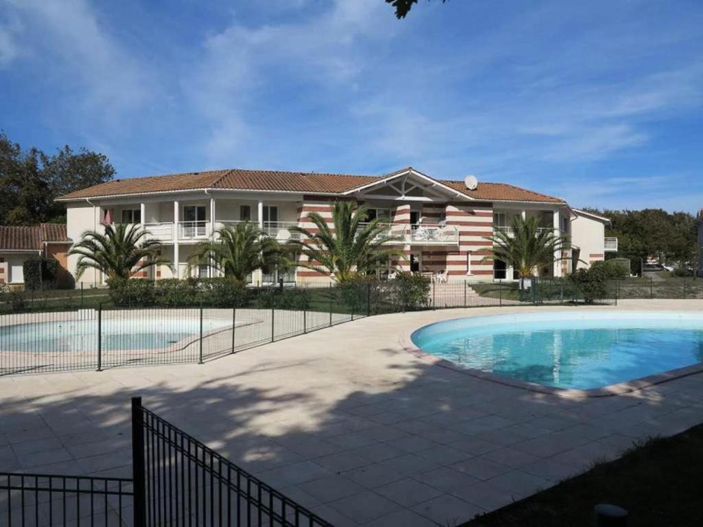 une maison avec une piscine devant une maison dans l'établissement Résidence Domaine Des Sables - 054 - Maison en duplex dans une résidence 3 étoiles MAE-2361, à Soulac-sur-Mer