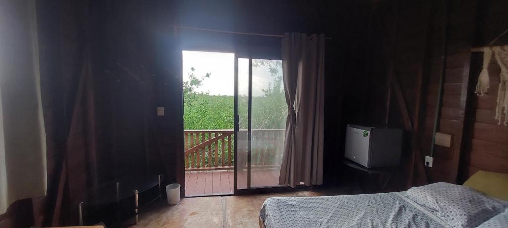 a bedroom with a bed and a sliding glass door at Cabaña Punta Cocos in Holbox Island