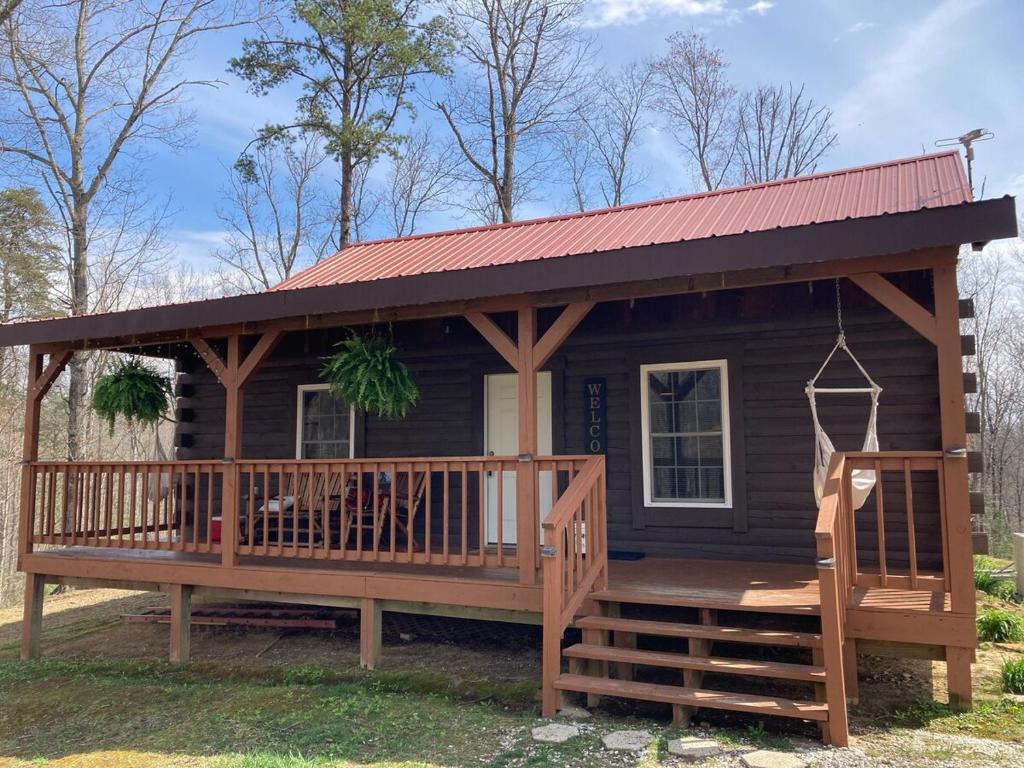 a log cabin with a deck and a red roof at The Willow, Secluded and Cozy country cabin in Ravenna