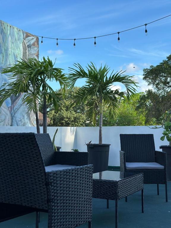 a patio with chairs and a table and palm trees at Calma Chicha Rooms in Playa del Carmen