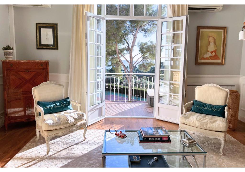 - un salon avec deux chaises et une porte ouverte dans l'établissement Charmant T3 Mont des Oiseaux 3 Etoiles - HYERES - Vue mer - Tennis, à Hyères