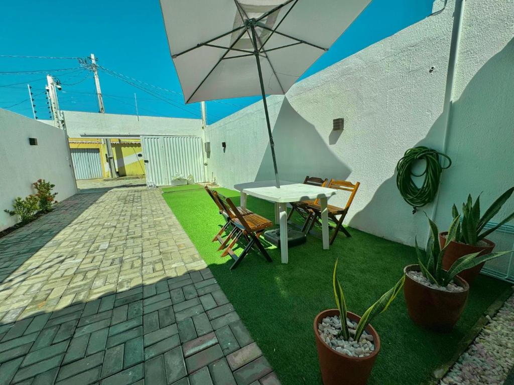 Un patio con una mesa y sillas y una sombrilla. en Bela acomodação em jacuipe com churrasqueira, piscina, mesa de sinuca e três quartos, dois sendo suítes! Além de muito espaço por toda a área!, en Barra do Jacuípe