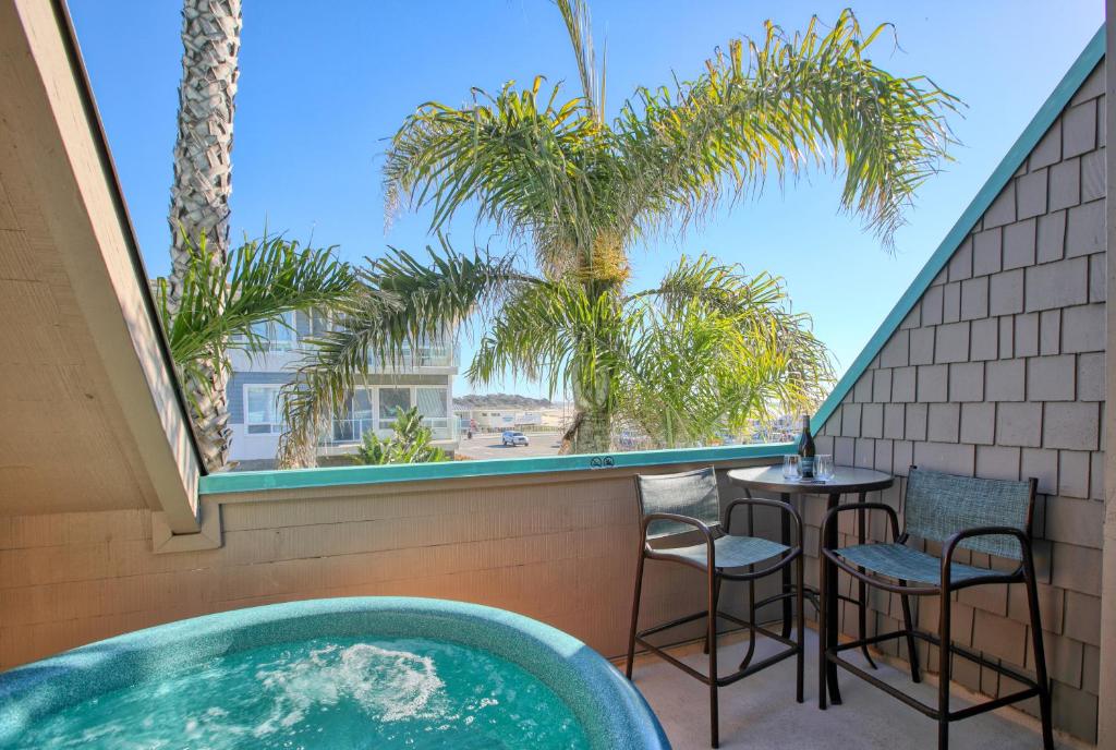 a balcony with a tub and chairs and palm trees at SeaVenture Beach Hotel in Pismo Beach