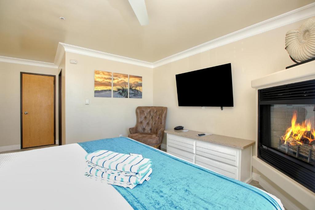 a bedroom with a bed with a fireplace and a tv at SeaVenture Beach Hotel in Pismo Beach
