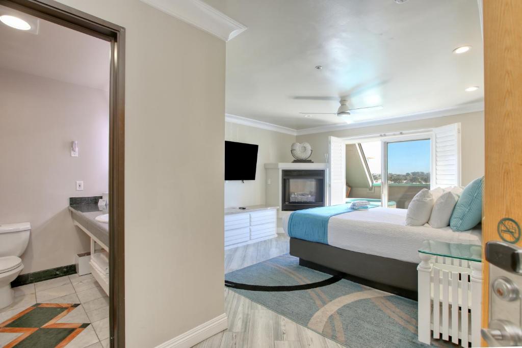 a bedroom with a bed and a tv and a bathroom at SeaVenture Beach Hotel in Pismo Beach