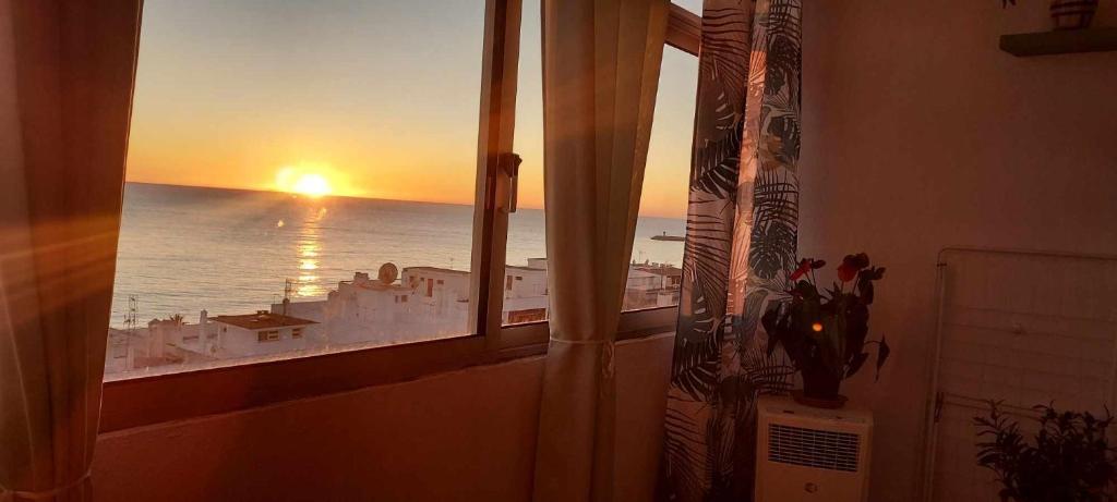 a window with a view of the ocean at sunset at Apartamento Quarteira Praia in Quarteira