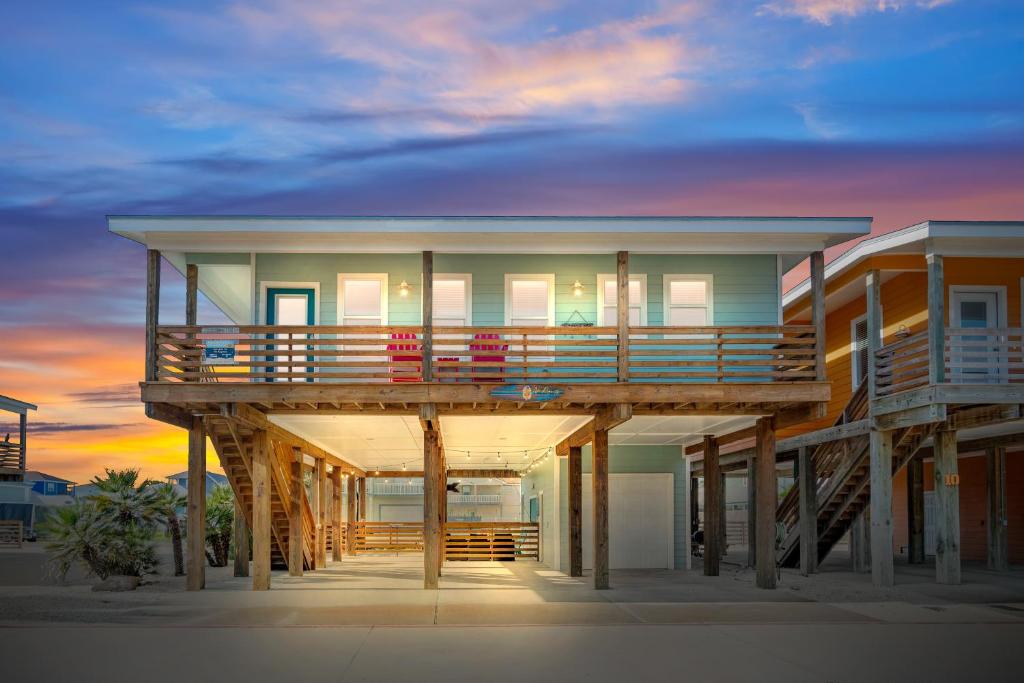 a house with a deck on the beach at sunset at No Regrets PET FRIENDLY in Port Aransas
