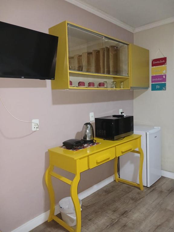 a yellow desk in a room with a microwave at Loft Confort in Pomerode