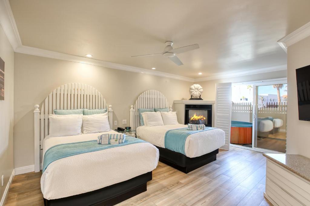 two beds in a bedroom with a fireplace at SeaVenture Beach Hotel in Pismo Beach