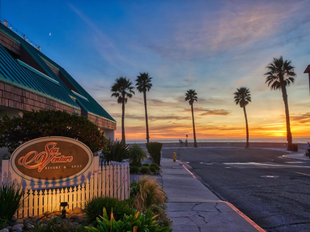 a sign for a hotel on the beach with palm trees at SeaVenture Beach Hotel in Pismo Beach