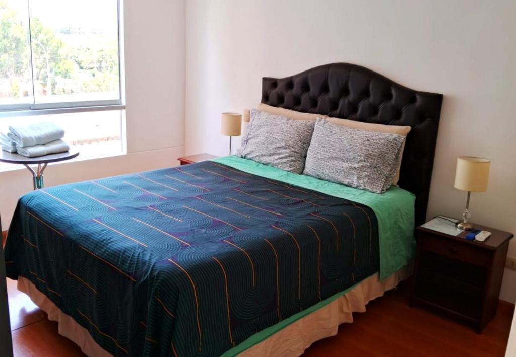 a bedroom with a large bed with a blue comforter at El Derby 511 Aparts de 3 Dorm con Aire Acondicionado in Lima