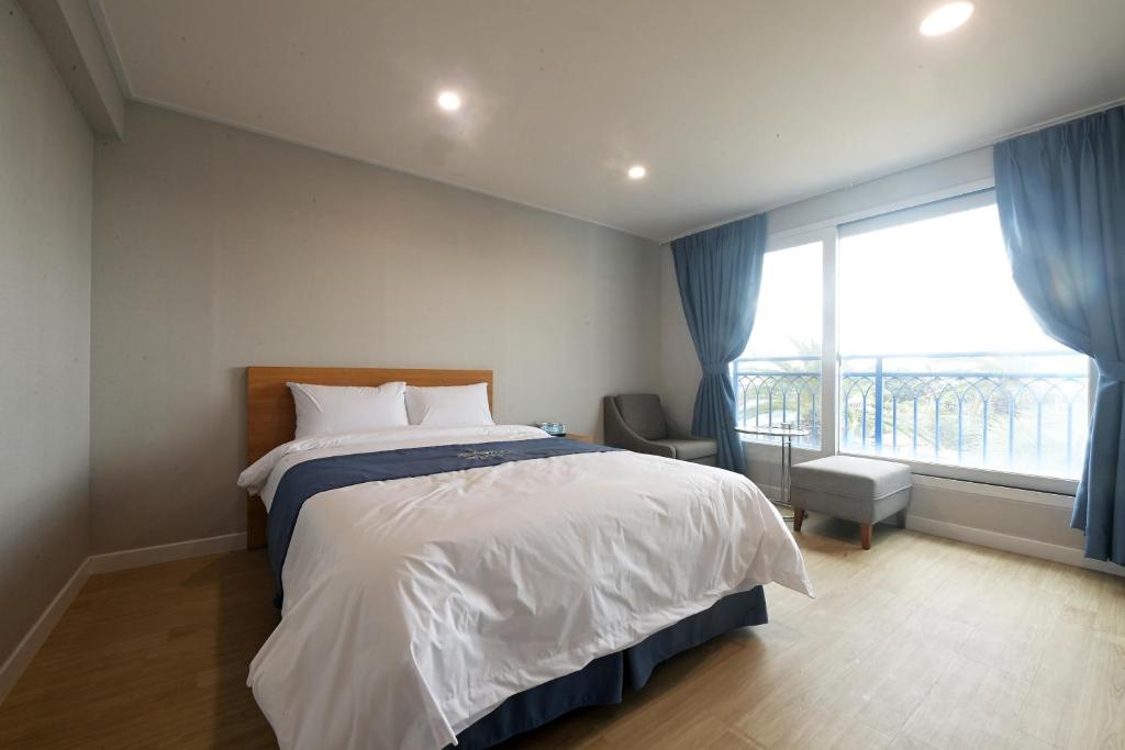 a bedroom with a bed and a large window at Sweet Stay Pension in Seogwipo
