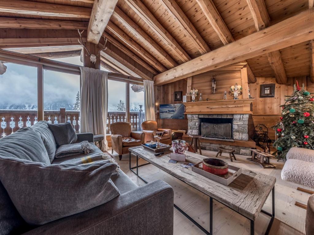 un soggiorno con divano e camino di Chalet à Courchevel avec piscine, jacuzzi et vue panoramique - FR-1-613A-13 a Courchevel
