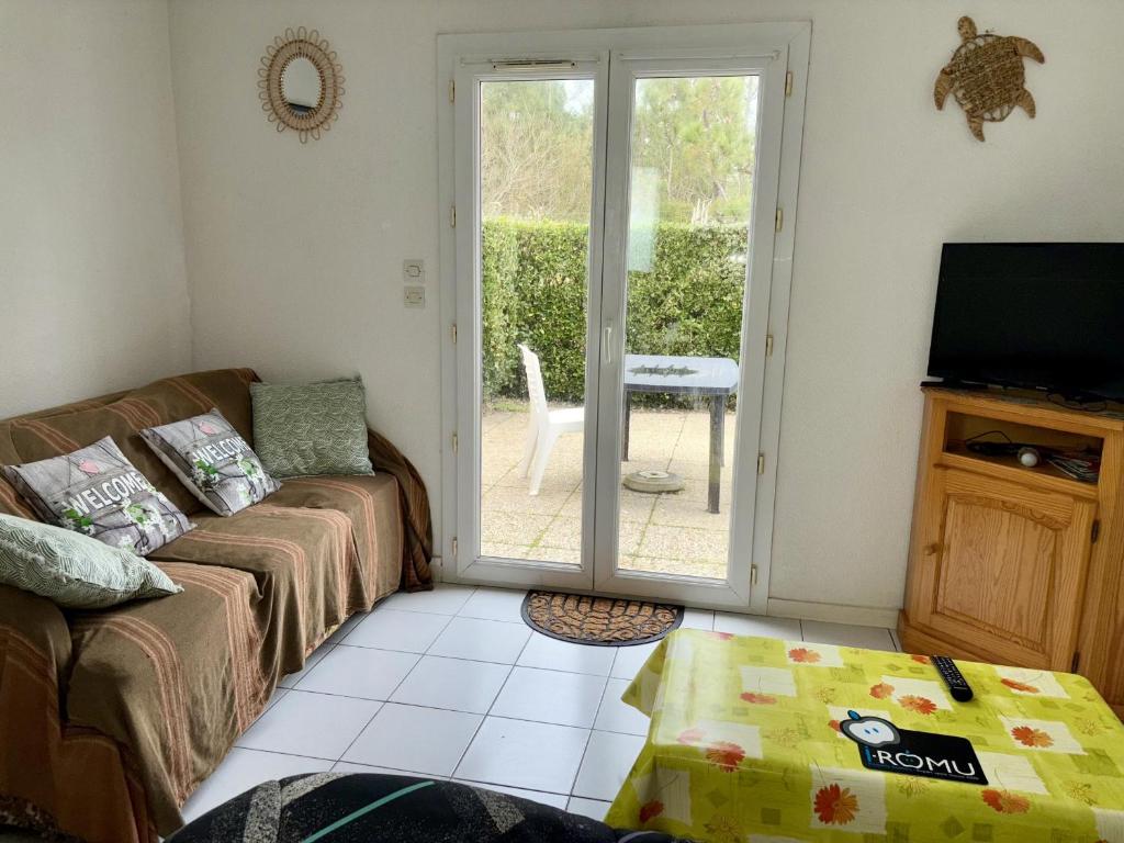 un salon avec un canapé et une porte coulissante en verre dans l'établissement Charmante maison de vacances à 400m de la plage - FR-1-323-565, à Saint-Hilaire-de-Riez