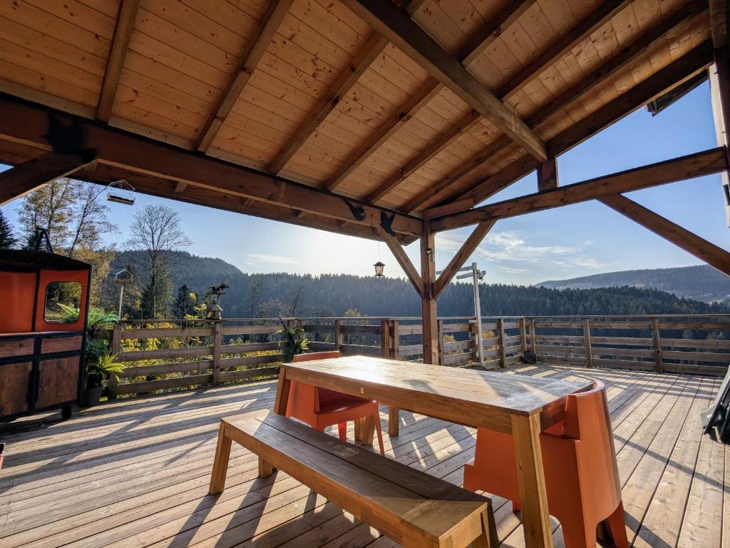 une table et un banc en bois sur une terrasse avec vue dans l'établissement Évasion montagne à Gérardmer avec terrasse et parking - FR-1-589-793, à Gérardmer