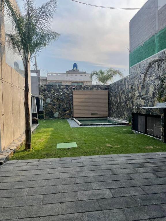 a yard with a stone wall and a building with a lawn at Casa las palmerasmeras in Chalco de Díaz Covarrubias