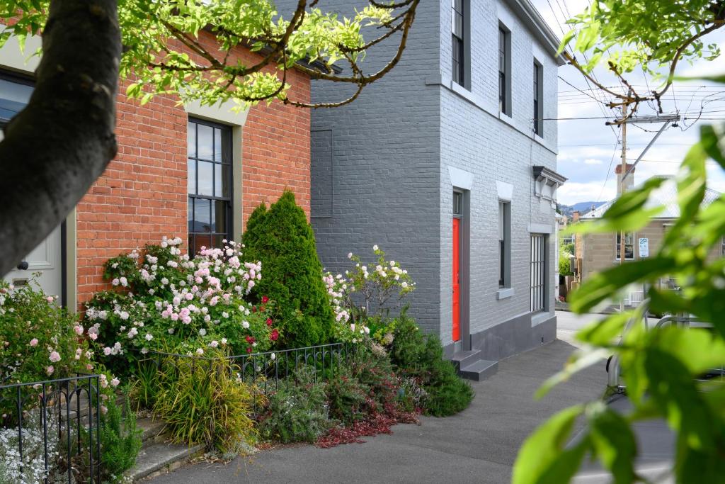 a brick building with flowers in front of it at DeWitt Apartment - 3 Red Doors Battery Point in Hobart