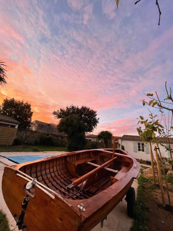 un bateau en bois assis dans une cour avec un coucher de soleil dans l'établissement Escapades Océanes Ile de Ré La Rochelle, à Sainte-Marie de Ré