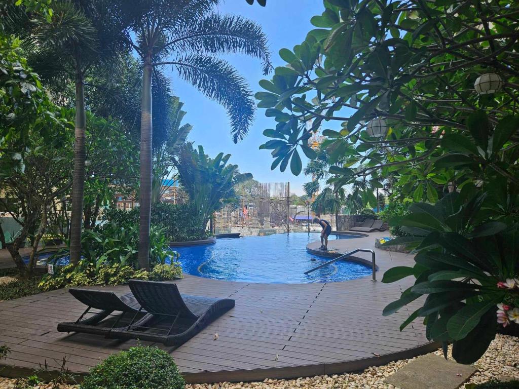 a swimming pool with two chairs and palm trees at 1Br QC Furnished Condo FREE Pool Access, FAST WIFI in Manila