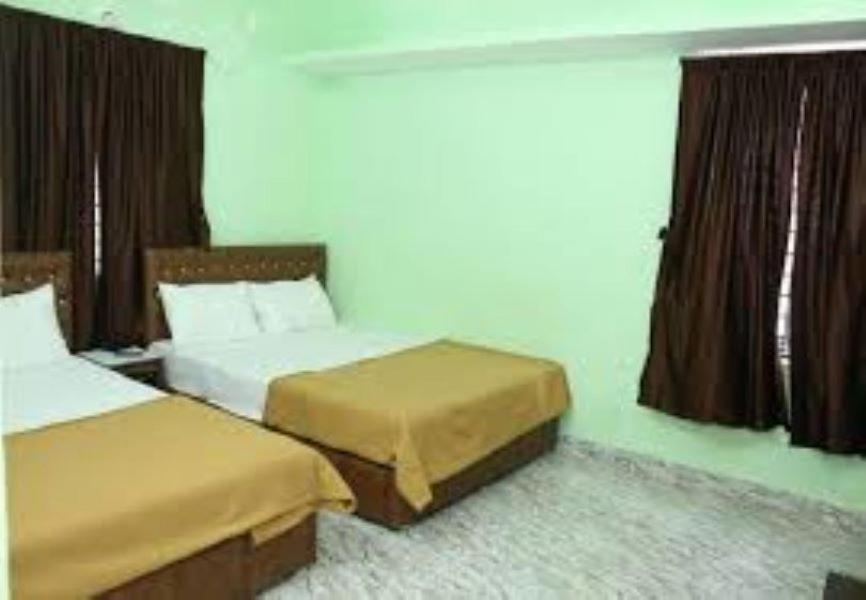 a hotel room with two beds and a window at Villa Saravana in Puducherry