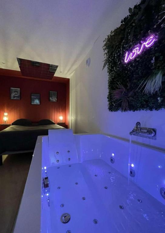 une salle de bain avec une baignoire avec une enseigne au néon sur le mur dans l'établissement Love room les étoiles du désir, à Périgueux